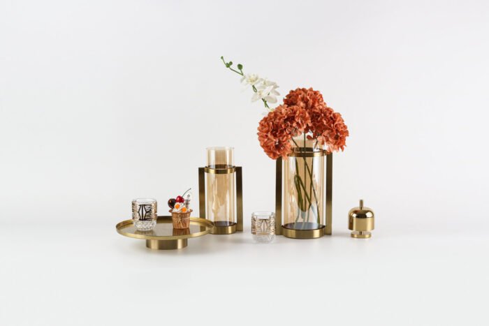 Modern gold display tray with elevated base and decorative items.