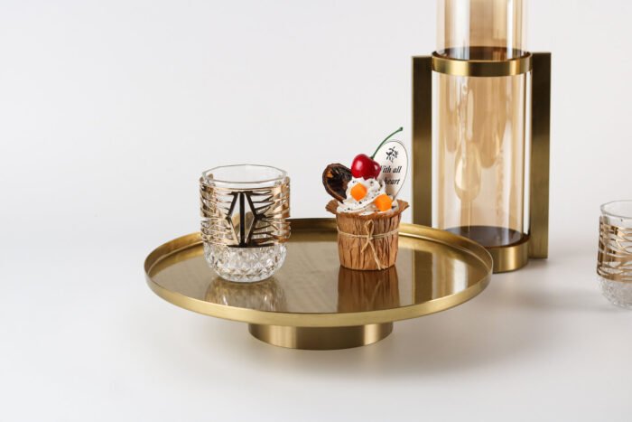 Modern gold display tray with elevated base and decorative items.