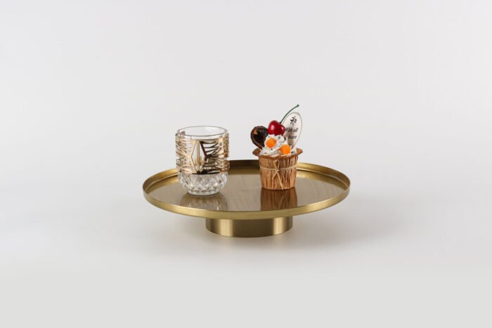 Modern gold display tray with elevated base and decorative items.