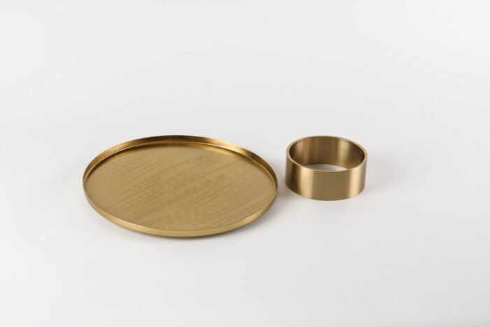 Modern gold display tray with elevated base and decorative items.