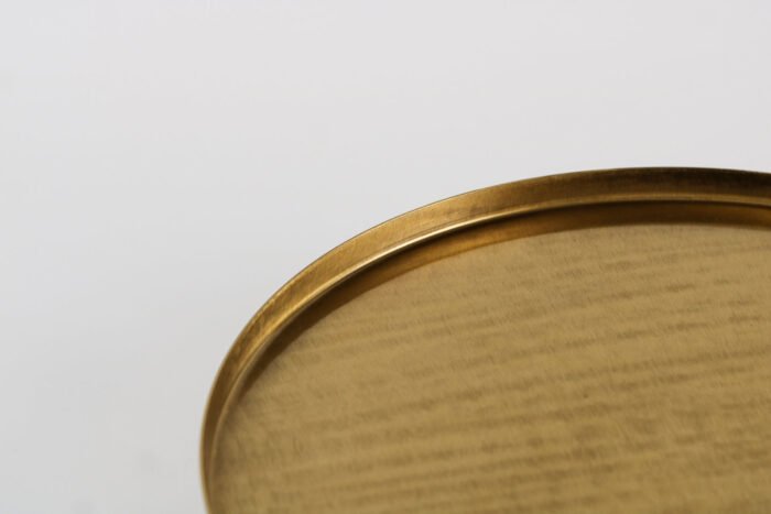 Modern gold display tray with elevated base and decorative items.
