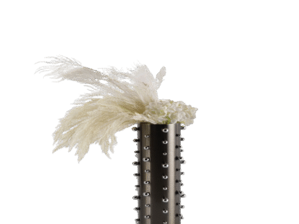 Tall studded silver vase with reflective finish and metallic stud details, styled with white dried florals in a minimalist space.